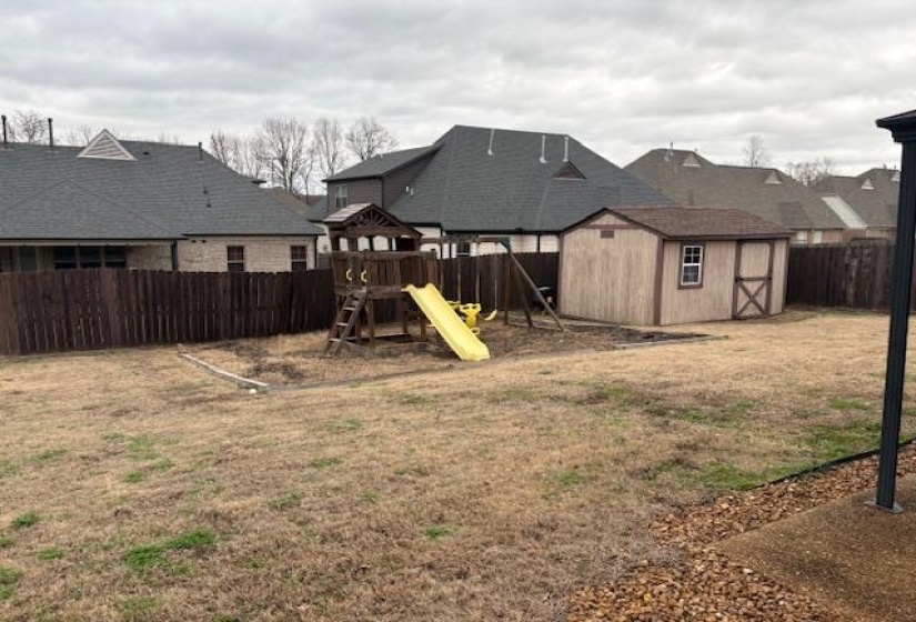 Fenced backyard with a playground and a shed