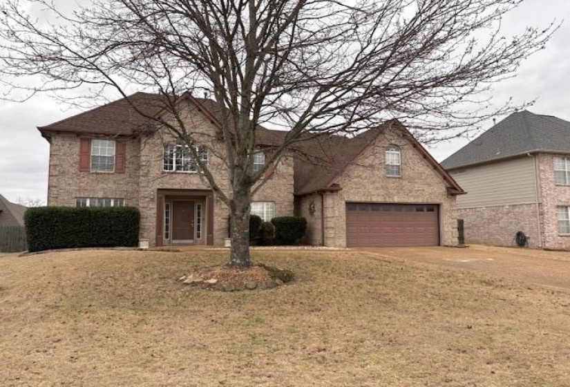 Traditional-style house featuring concrete driveway, a garage, brick siding, and a front lawn