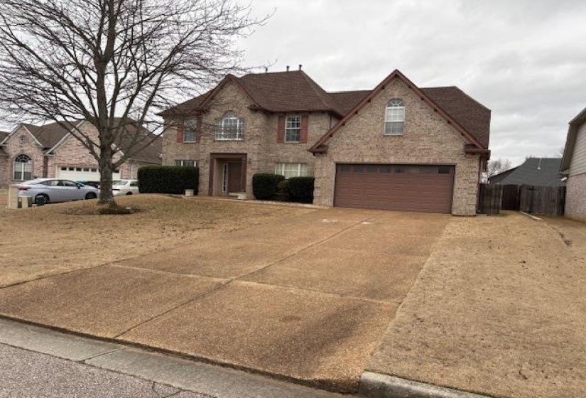 View of front facade featuring concrete driveway and brick siding
