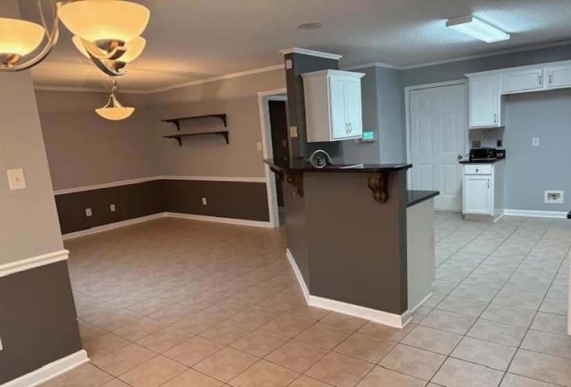Kitchen with white cabinets, ornamental molding, a breakfast bar area, a peninsula, and light tile patterned floors