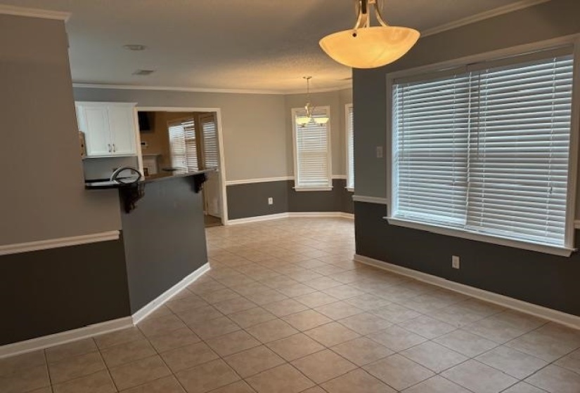 Kitchen with dark countertops, a kitchen breakfast bar, ornamental molding, light tile patterned flooring, and white cabinetry