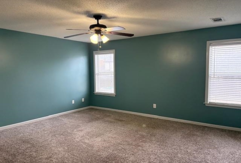 Carpeted empty room with a textured ceiling and a ceiling fan