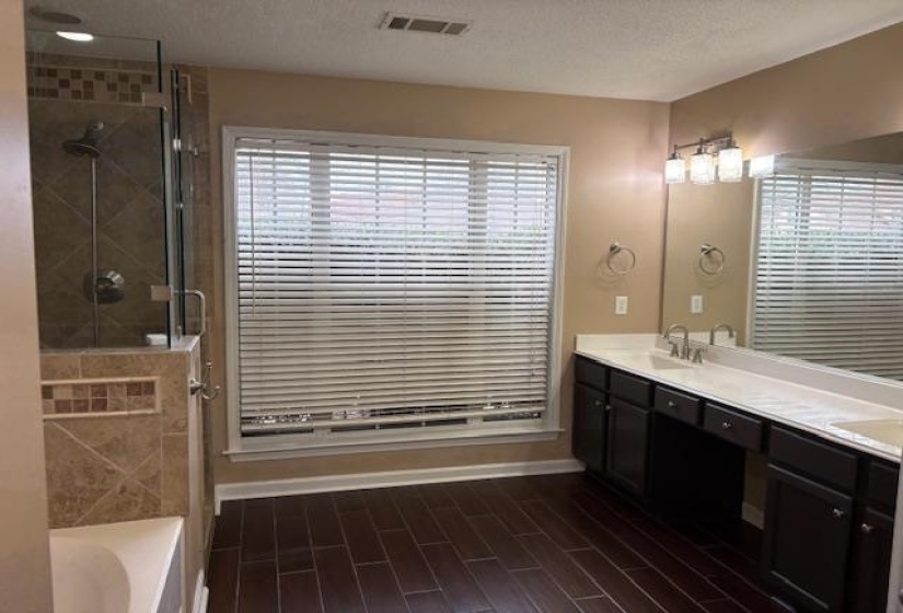 Bathroom featuring double vanity, a shower stall, a textured ceiling, a bath, and wood tiled floors