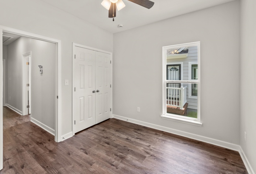 Unfurnished bedroom featuring dark wood-style floors, a closet, a ceiling fan, and attic access