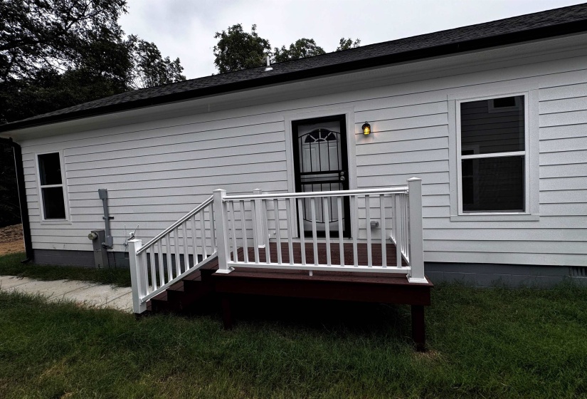 Entrance to property featuring a deck, roof with shingles, and a yard