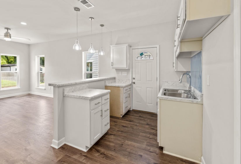 Kitchen featuring light countertops, white cabinetry, hanging light fixtures, dark wood-style floors, and recessed lighting