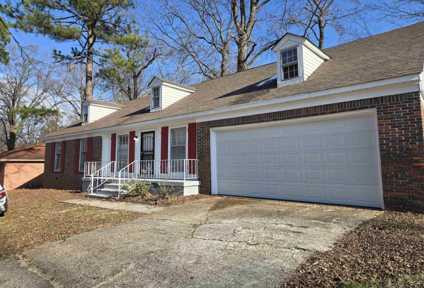 Cape cod home with brick siding, a garage, driveway, and a shingled roof