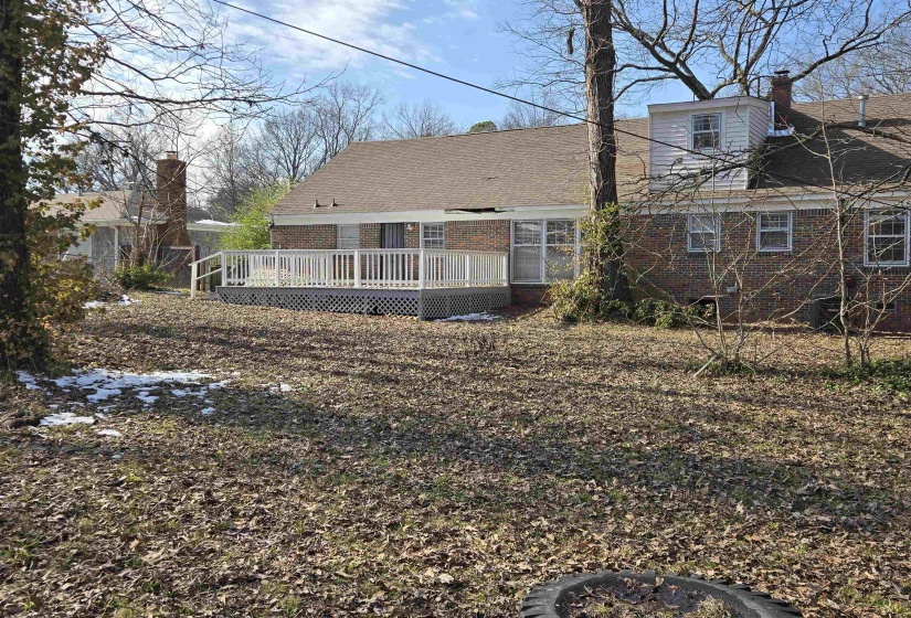 Back of property featuring a chimney, brick siding, and a wooden deck