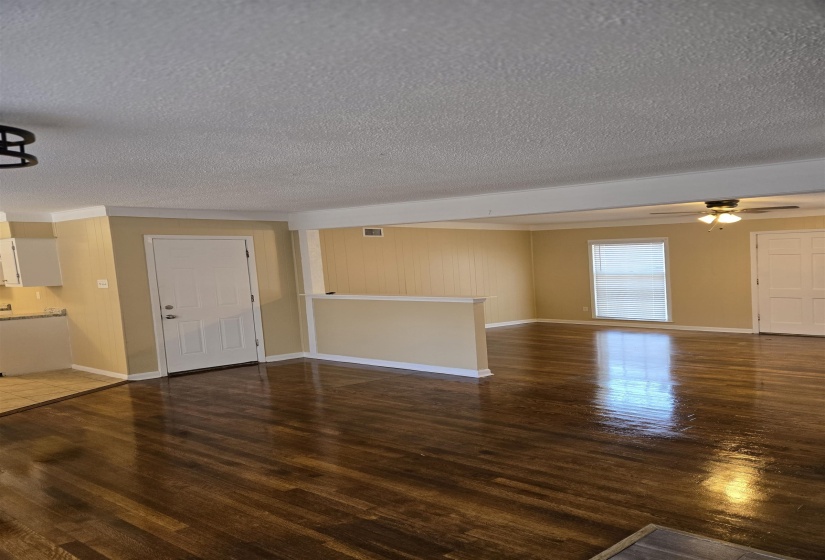 Unfurnished living room with a ceiling fan, wood finished floors, visible vents, and baseboards