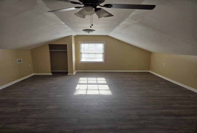 Upstairs BONUS room featuring dark wood finished floors, visible vents, baseboards, and a ceiling fan