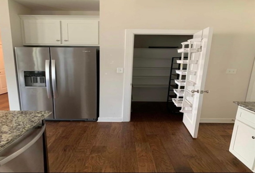 Kitchen with white cabinetry, stainless steel appliances, dark stone counters, and dark wood-type flooring