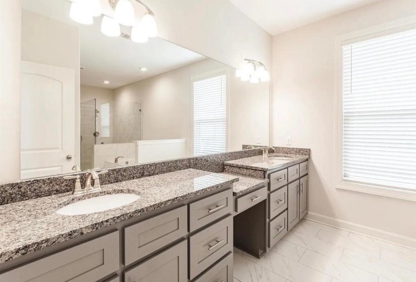 Full bathroom featuring a walk in shower, two vanities, and light marble finish floors
