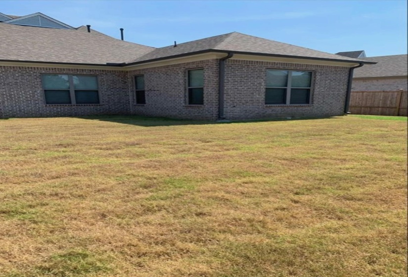 Back of property with brick siding and roof with shingles