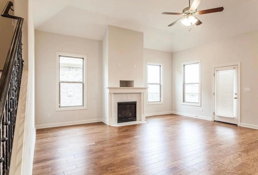 Unfurnished living room with light wood finished floors, healthy amount of natural light, stairs, a ceiling fan, and vaulted ceiling