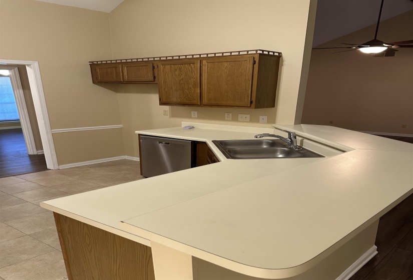 Kitchen with sink, stainless steel dishwasher, ceiling fan, light tile patterned floors, and kitchen peninsula