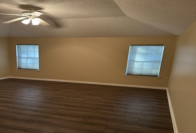Empty room featuring dark hardwood / wood-style flooring, a healthy amount of sunlight, and a textured ceiling