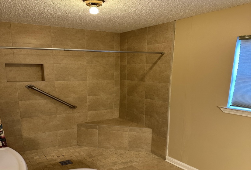 Bathroom with toilet, a textured ceiling, and a tile shower
