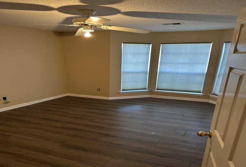 Spare room featuring a textured ceiling, ceiling fan, and dark wood-type flooring