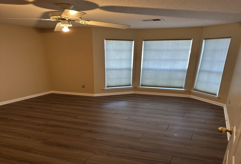 Empty room with a textured ceiling, ceiling fan, and dark wood-type flooring