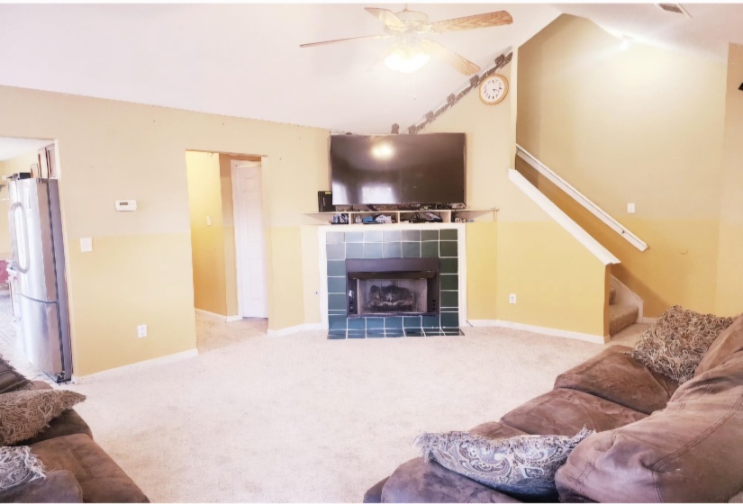 Living room with a tile fireplace, light carpet, and ceiling fan