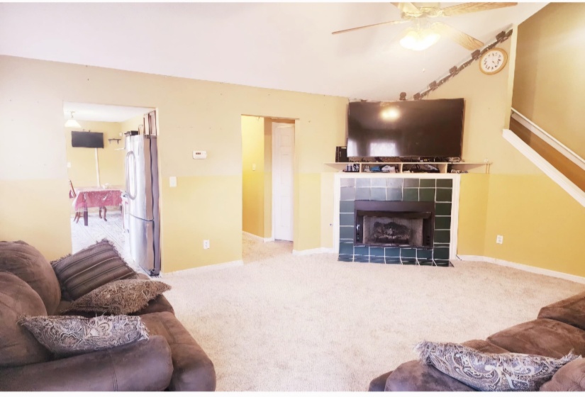 Carpeted living room with ceiling fan and a fireplace