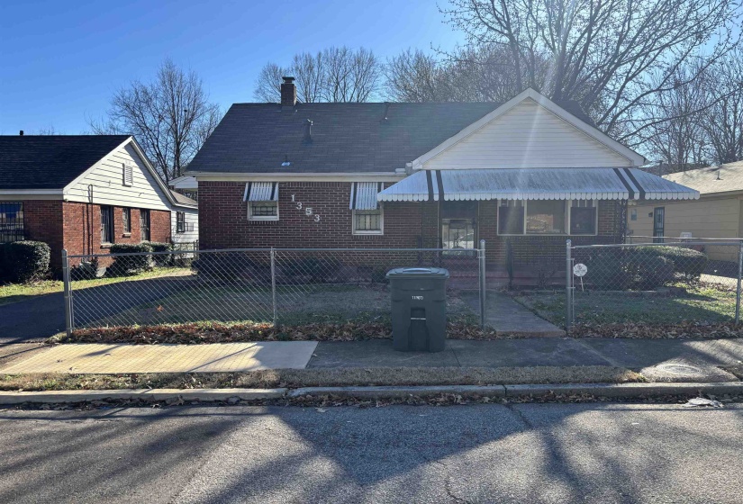 Bungalow-style house with brick siding, a fenced front yard, a chimney, and a gate