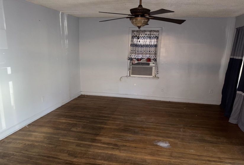 Empty room featuring dark wood finished floors, ceiling fan, a textured ceiling, and cooling unit