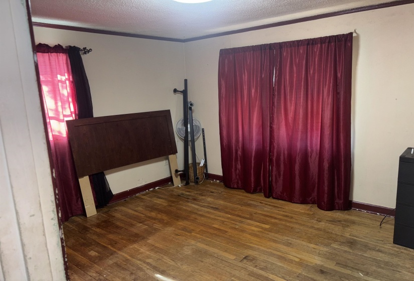 Unfurnished bedroom with dark wood-style floors and a textured ceiling