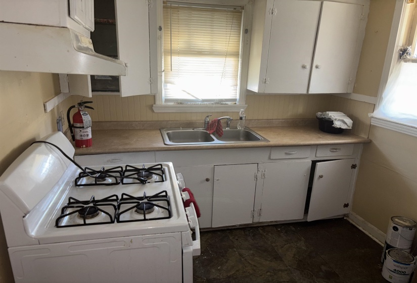 Kitchen with white gas stove, white cabinetry, under cabinet range hood, and light countertops