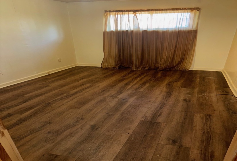 Spare room featuring dark wood-style floors and baseboards