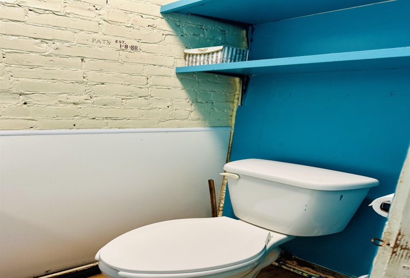 Bathroom featuring toilet and brick wall