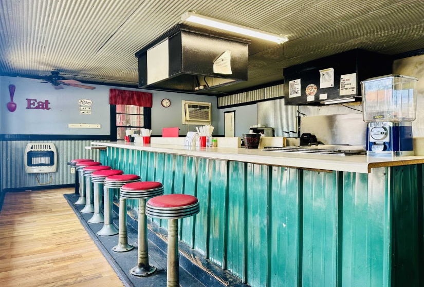 Bar featuring heating unit, wood finished floors, a ceiling fan, extractor fan, and a wall mounted air conditioner