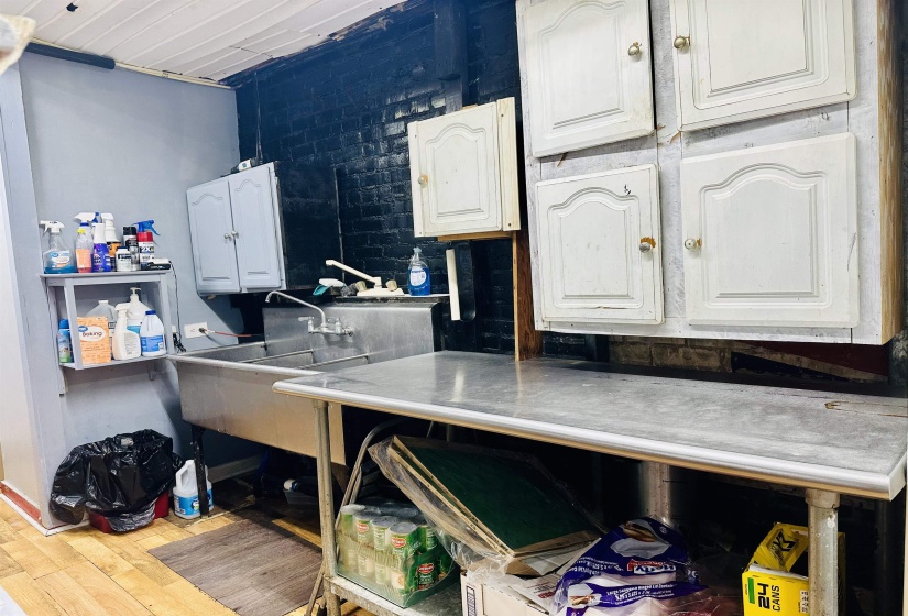 Kitchen with white cabinets, wood finished floors, and a sink
