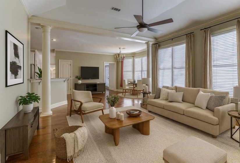 Living area with decorative columns, crown molding, wood finished floors, ceiling fan, and a chandelier