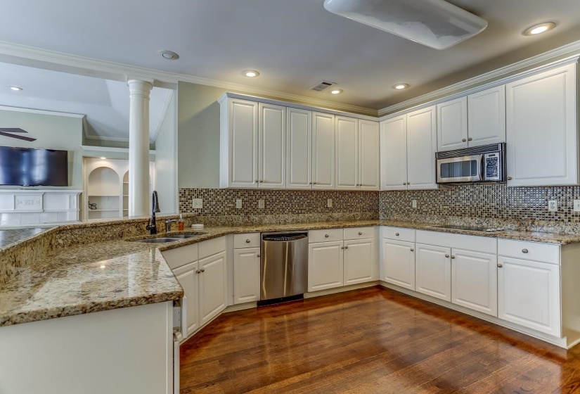 Kitchen with sink, light stone counters, dark hardwood / wood-style flooring, white cabinets, and appliances with stainless steel finishes