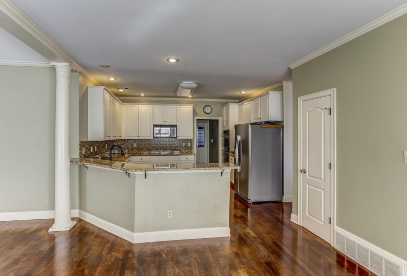 Kitchen featuring kitchen peninsula, appliances with stainless steel finishes, backsplash, light stone counters, and white cabinetry