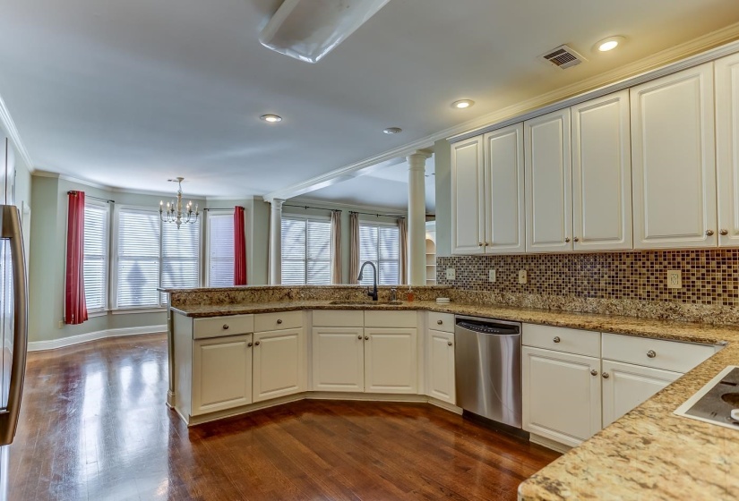 Kitchen with kitchen peninsula, stainless steel dishwasher, sink, decorative light fixtures, and white cabinets