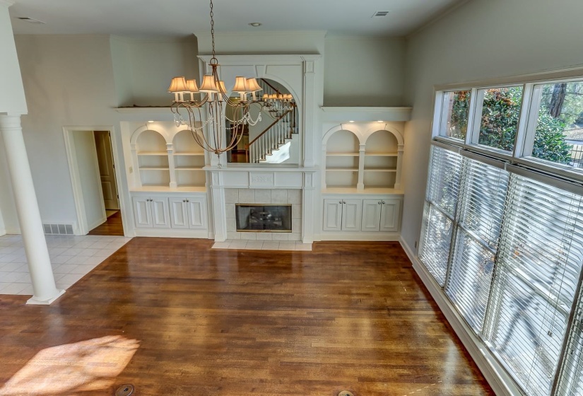 Unfurnished living room featuring tile patterned floors, a notable chandelier, built in features, and a tile fireplace