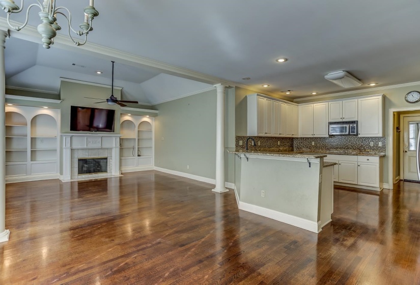 Kitchen with kitchen peninsula, light stone counters, a breakfast bar, white cabinetry, and lofted ceiling