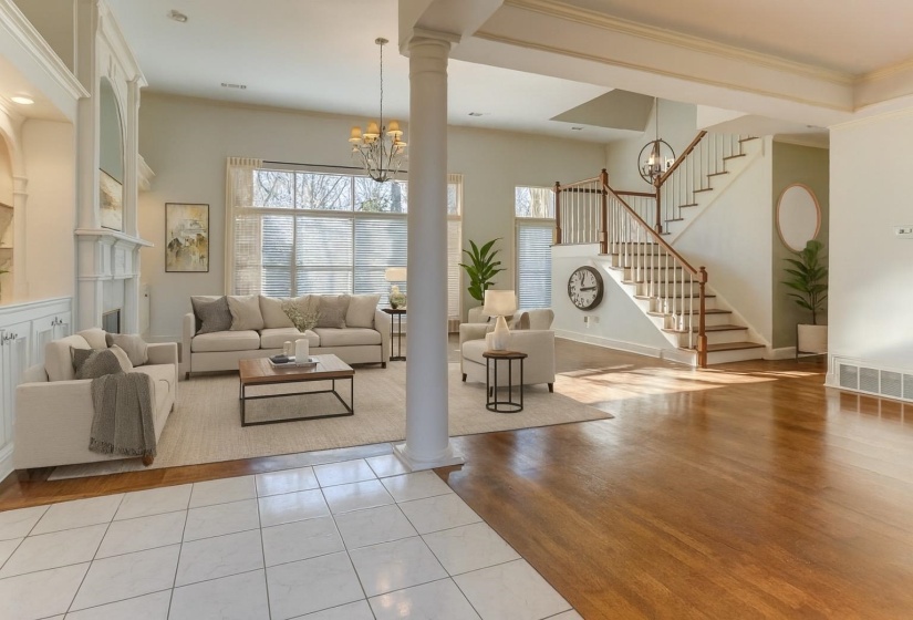Living area featuring a chandelier, light wood-style flooring, ornamental molding, stairway, and a fireplace