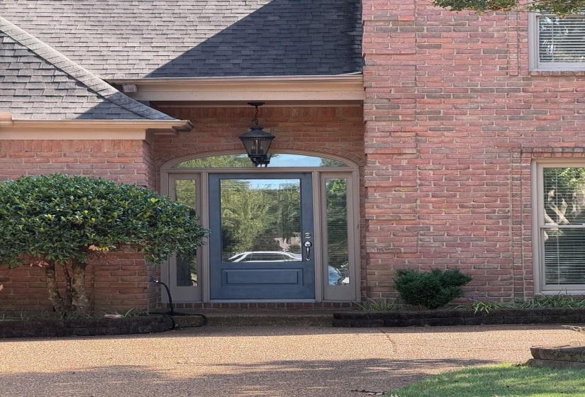 Property entrance featuring a shingled roof and brick siding