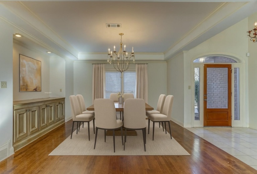 Dining space featuring a chandelier, light wood-type flooring, a tray ceiling, and crown molding
