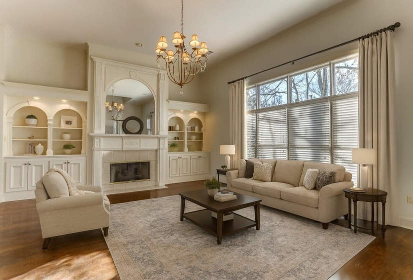 Living room with a chandelier, dark wood-type flooring, and a tile fireplace