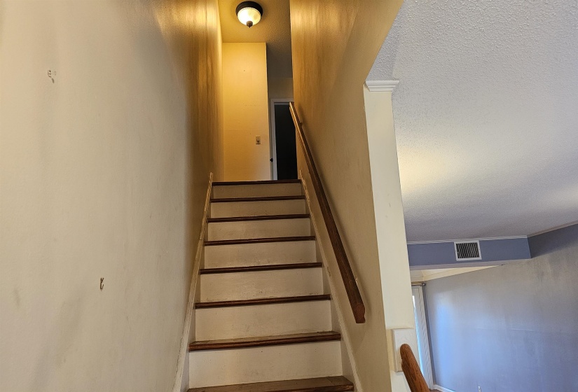 Stairway featuring a textured ceiling