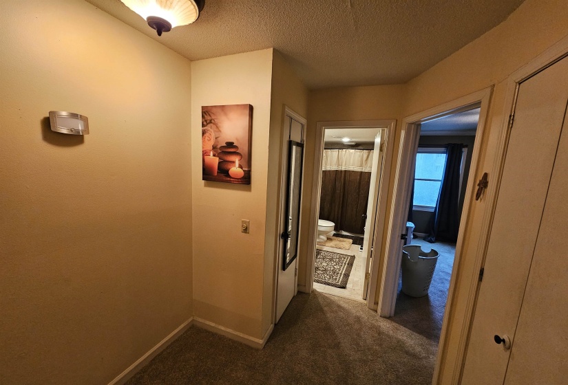 Hall with dark carpet, a textured ceiling, and baseboards