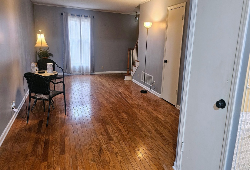 Living area with stairs, dark wood finished floors, and crown molding