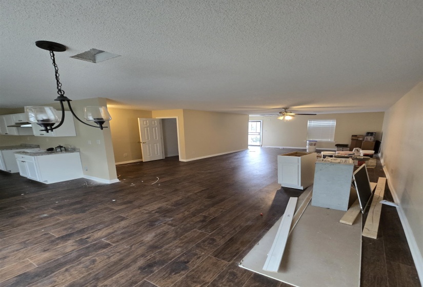 Living room featuring dark hardwood / wood-style flooring, ceiling fan with notable chandelier, and a textured ceiling