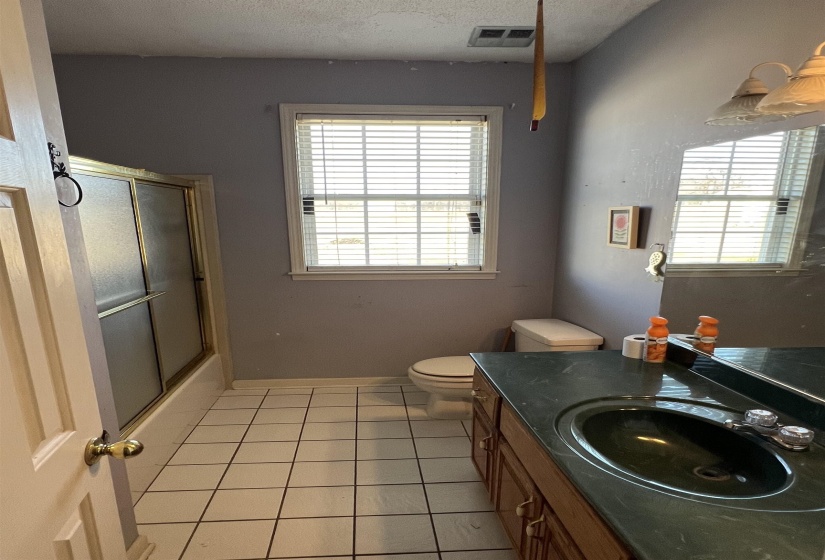 Full bathroom featuring vanity, light tile patterned floors, plenty of natural light, and a textured ceiling