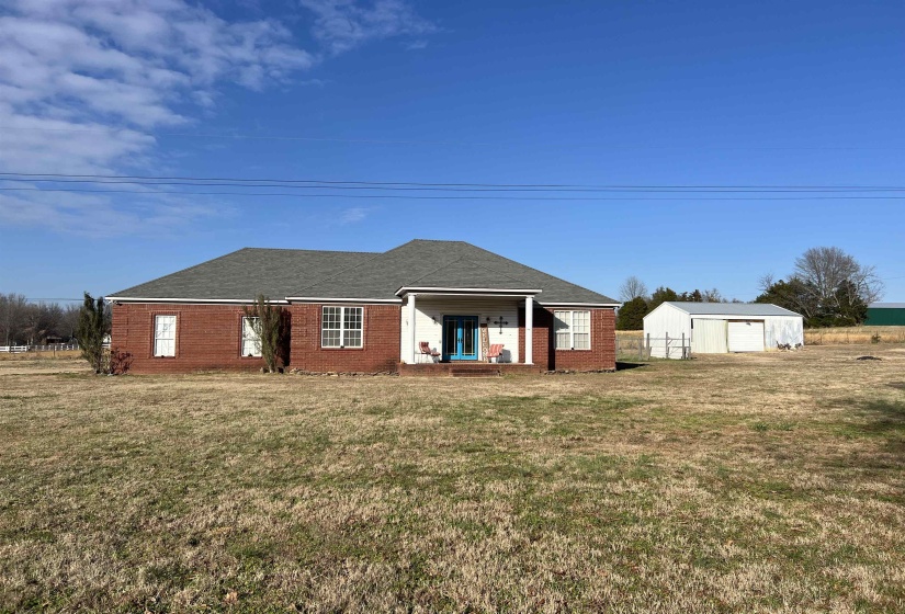 Front view of house featuring a lawn, an outbuilding, brick siding, and roof with shingles