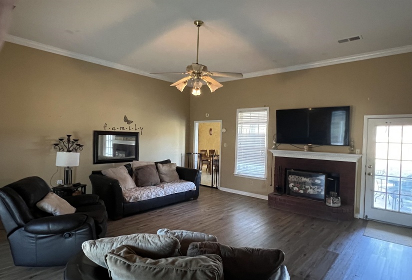 Living room with a glass covered fireplace, wood finished floors, ornamental molding, and ceiling fan